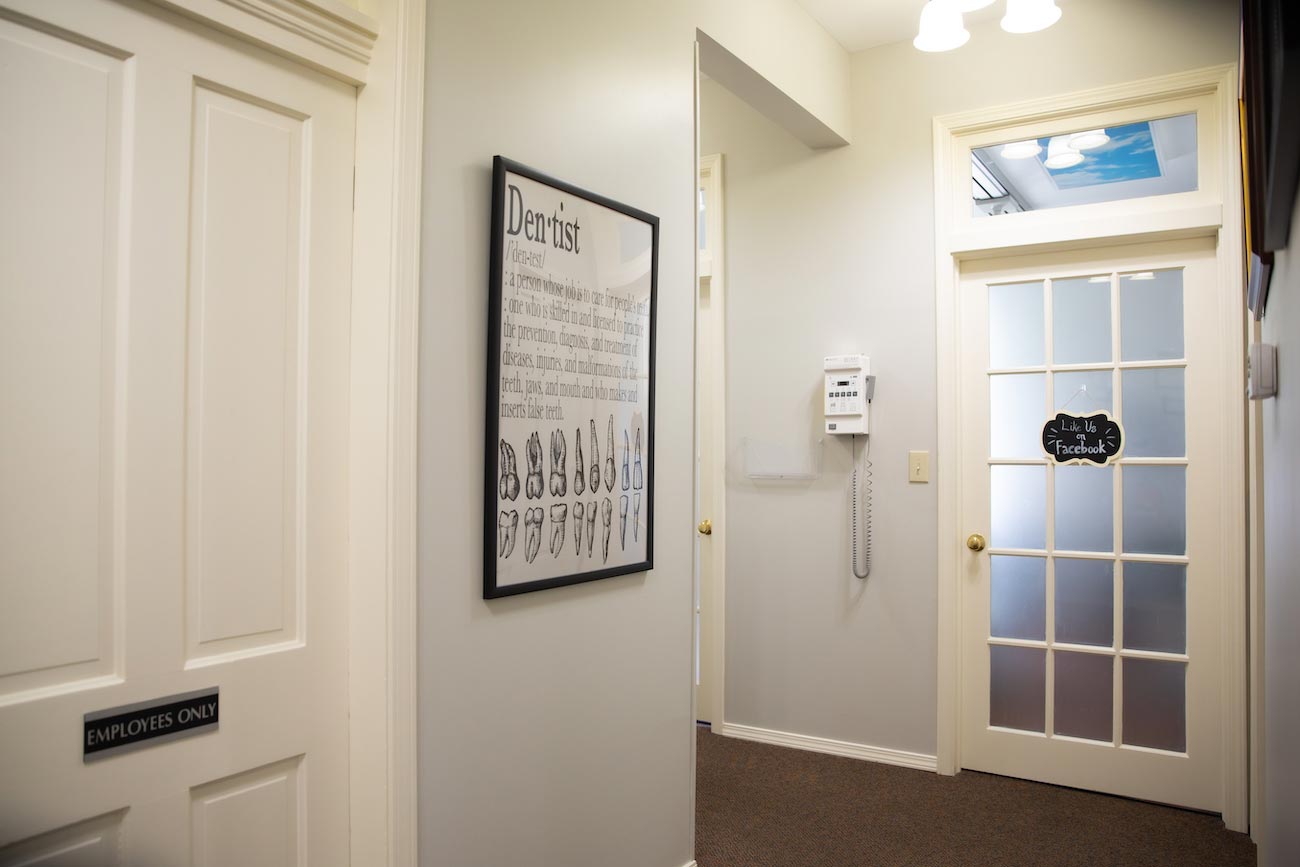 The image shows an interior hallway with a sign on the wall, a door on the right, and a framed picture hanging above the door.