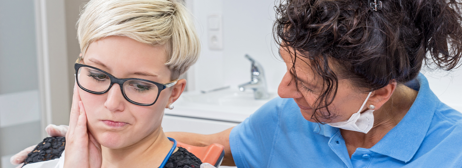 The image shows a dental professional assisting a patient during a dental appointment.