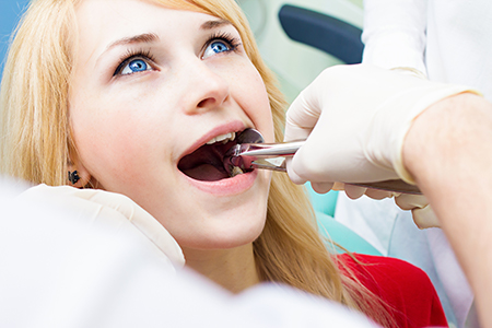 A woman with blue eyes receiving dental care from a dentist wearing gloves.