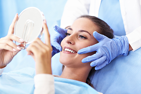 The image shows a person sitting on a dental chair with their eyes closed while a dental professional takes care of them, with a mirror reflecting the process.