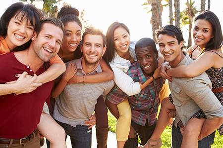 A group of people posing together outdoors, smiling and embracing each other.