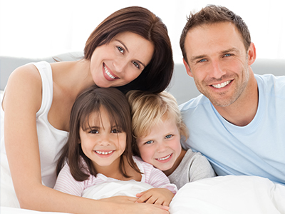 A family posing together on a bed with a warm, happy atmosphere.